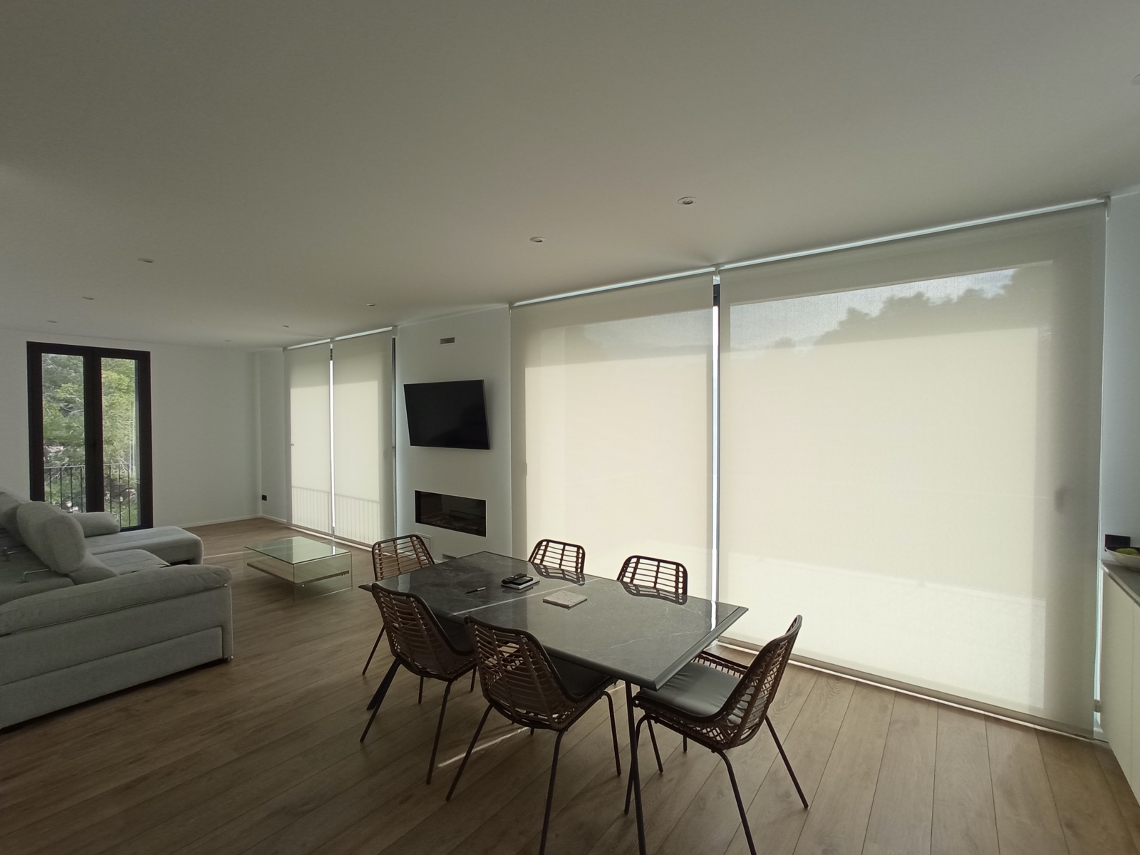 Estores enrollables screen en salón amplio con chimenea